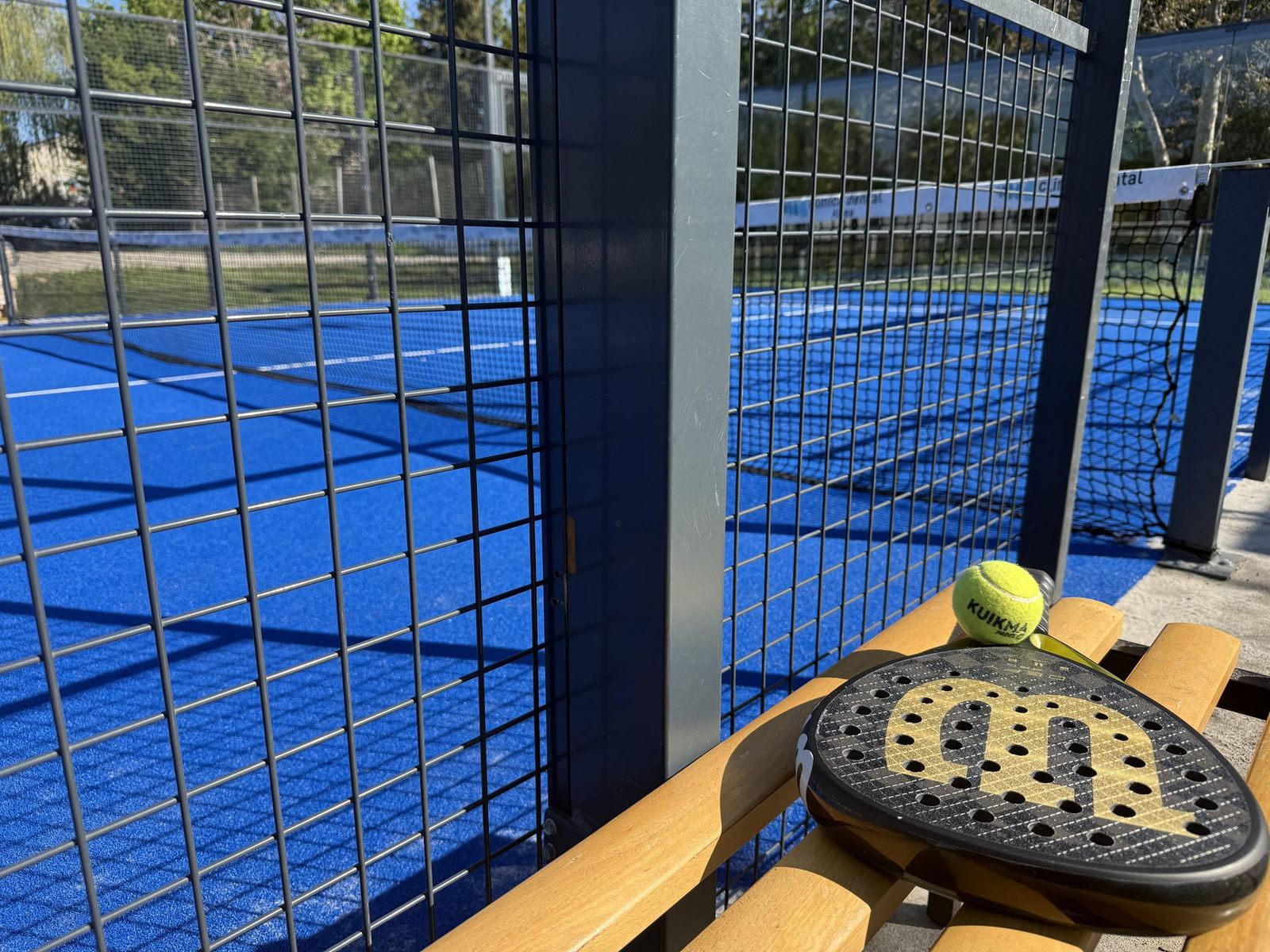 Padel-Schläger und Ball auf einer Holzbank am Court