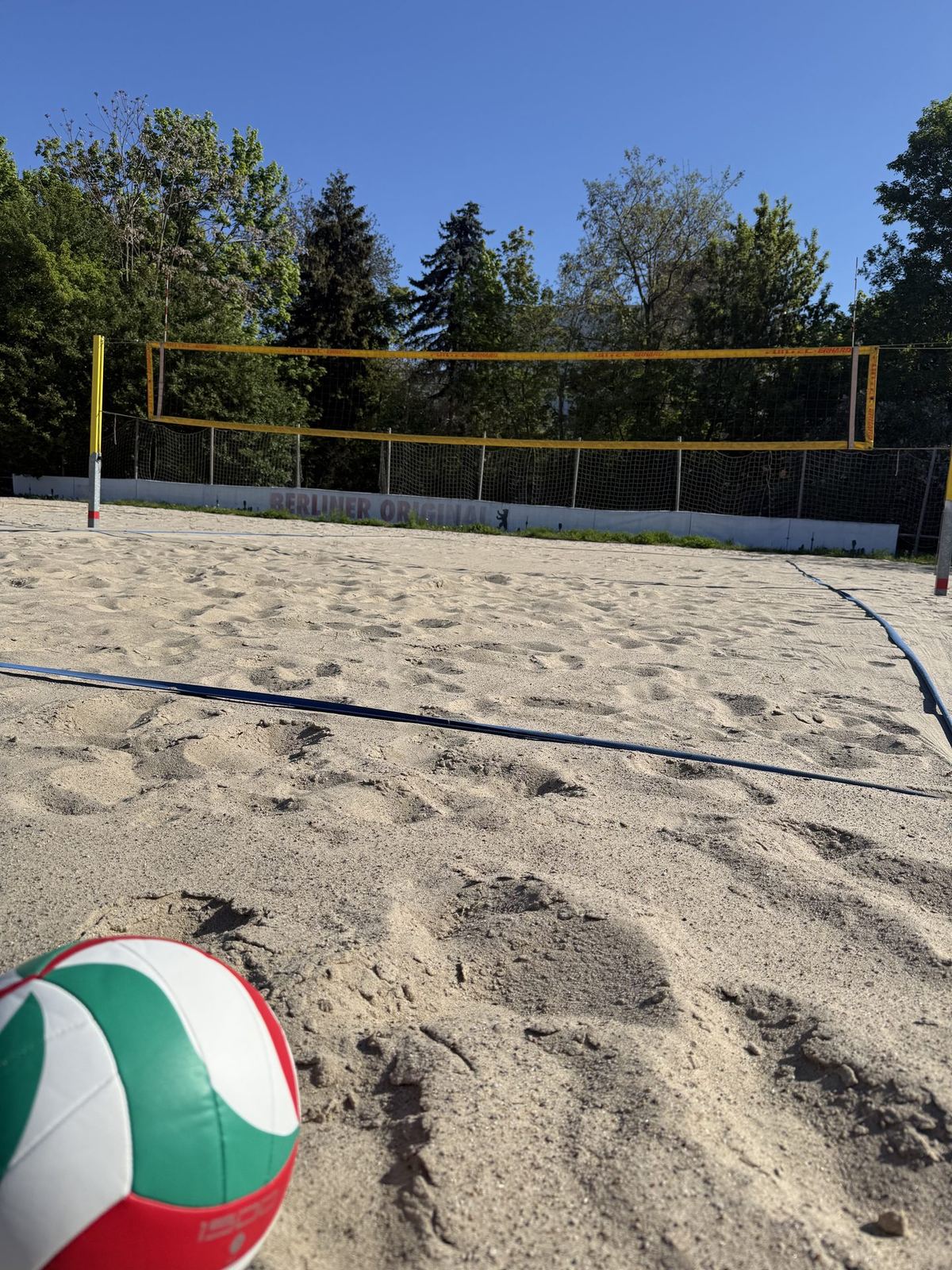 Sandfläche mit Volleyball im Vordergrund