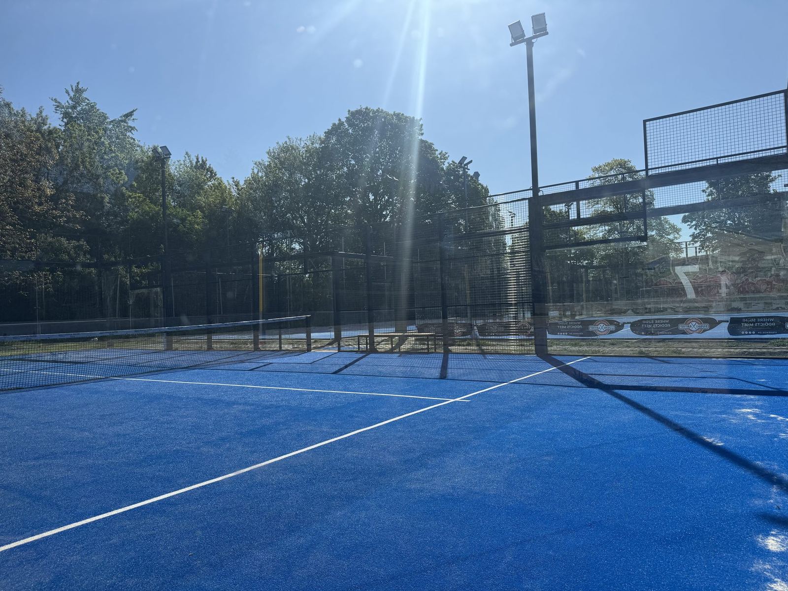 Padel Court mit Sonnenstrahl und Flutlicht-Mast