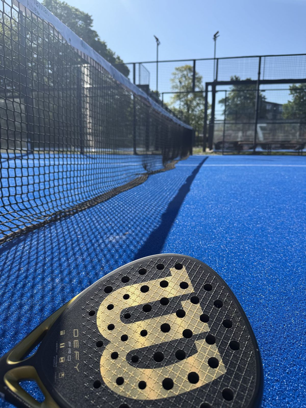 Padel-Schläger groß im Vordergrund auf einem Court