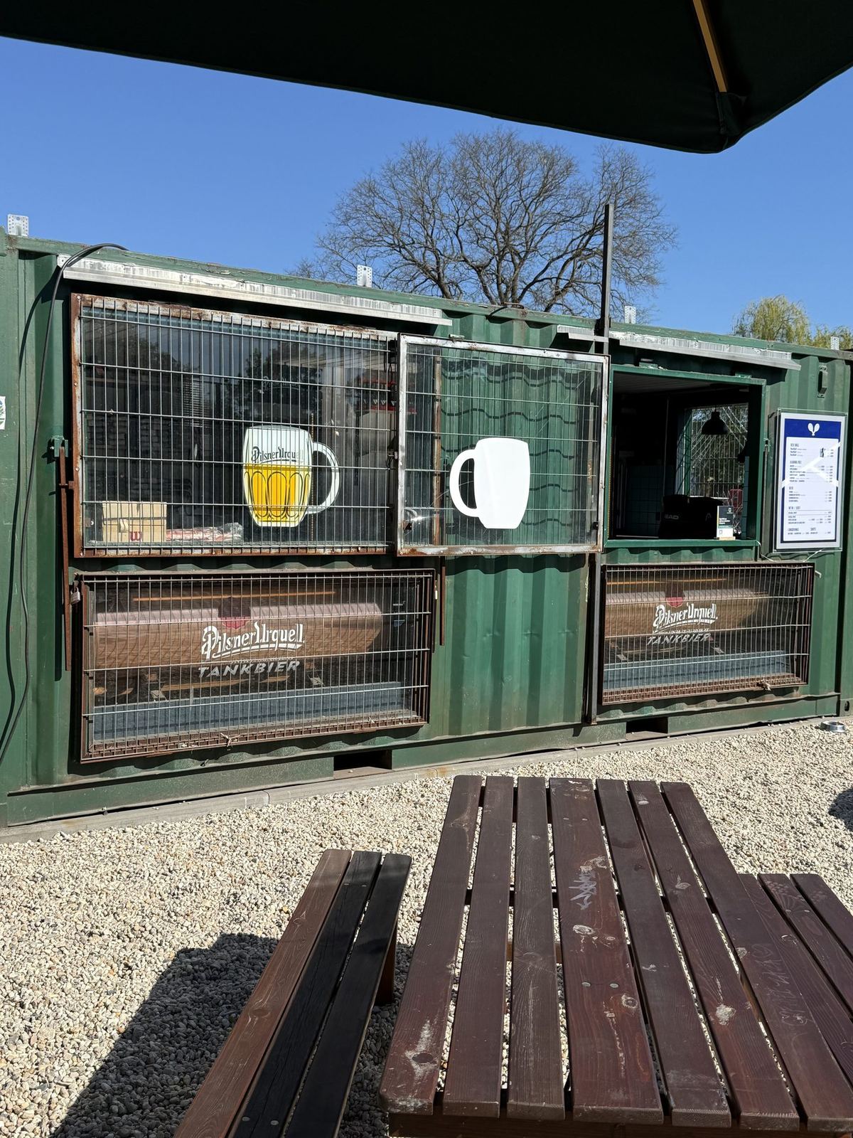 Container-Bar mit Pilsner Urquell Tankbier und Holztischen im Biergarten